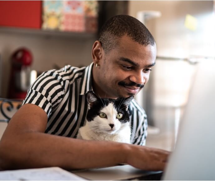 男人抱著貓使用筆記型電腦